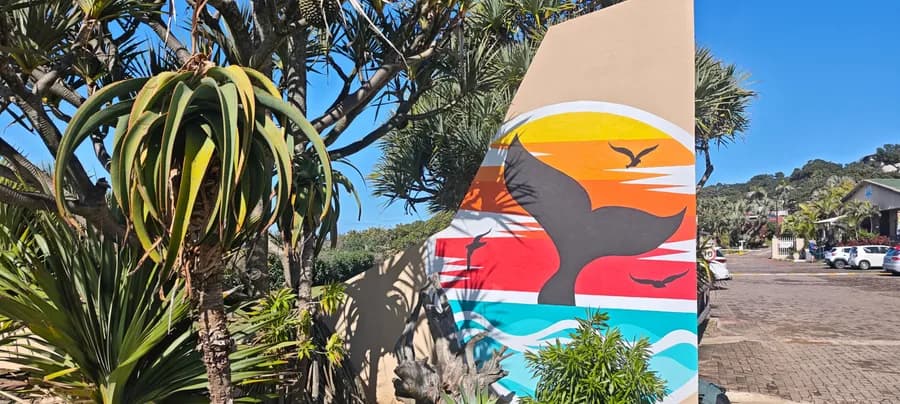 Painted sunset and whale-tail mural at the estate entrance