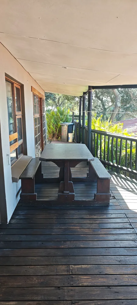 Covered veranda with a long wooden table and benches