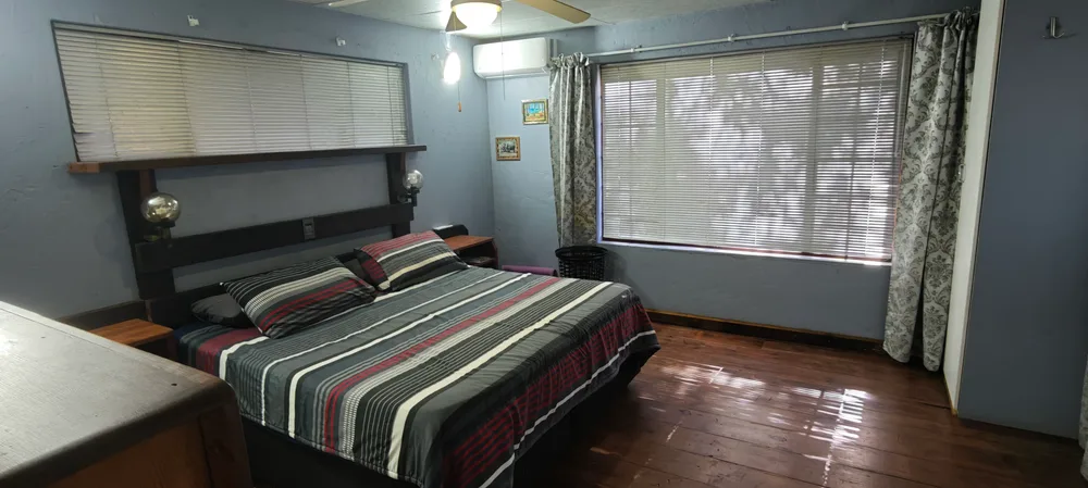 Bedroom with a double bed, ceiling fan and wooden floors